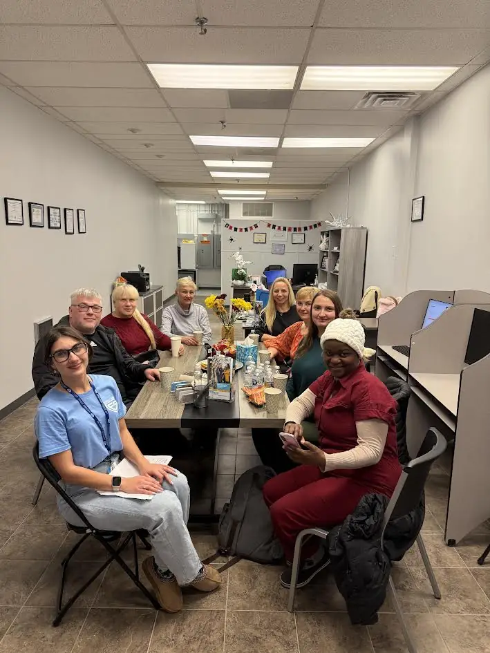 Caregivers and staff share coffee around a long table during a team meeting at the European Service home care office in Niles, Illinois.