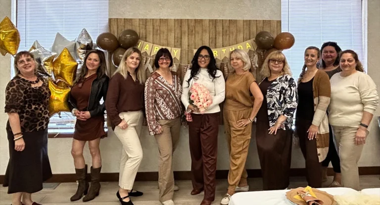 European Service office staff lined up for a team birthday photo with gold star balloons and a Happy Birthday banner.
