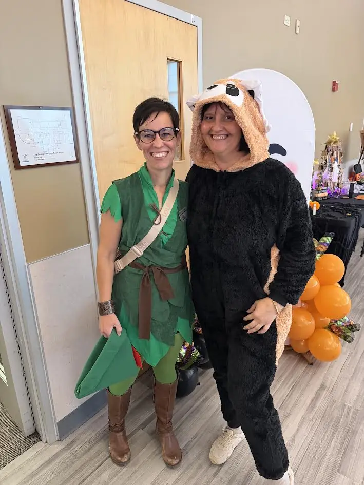 Two European Service team members in Halloween costumes, one dressed as a storybook character, at a community Boo Bash event.