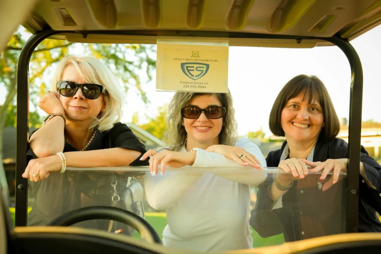Three European Service team members in a golf cart marked “Golf carts sponsored by European Service LLC” at a community golf outing.