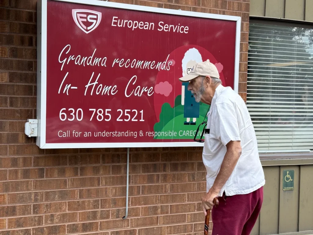 Senior man with a cane passing the in-home care sign at the European Service office in Lombard, Illinois.